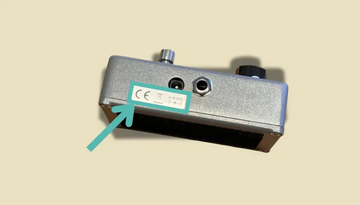 Close-up of a guitar pedal power label, showing the voltage rating you should check before plugging in.