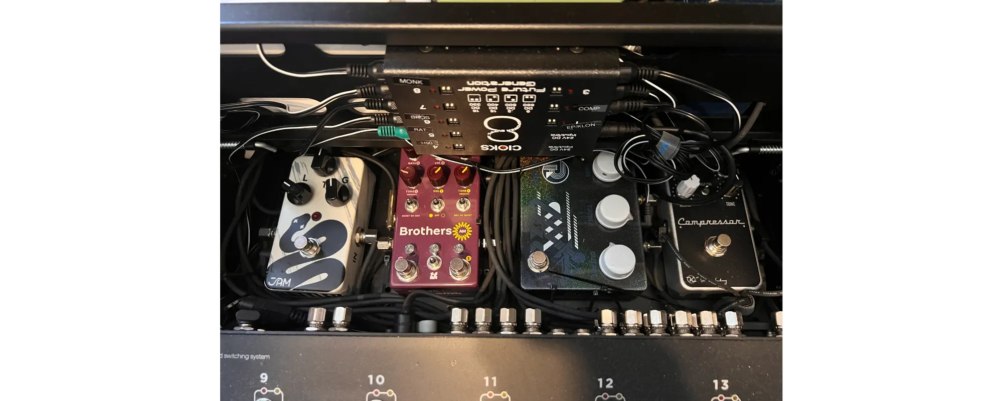 The underside of Gareth's two-tier pedalboard, showing a Cioks 8 expander (adding extra isolated outputs to the DC7 hidden behind it) mounted between the tiers, with loose, untied power and patch cabling running to the pedals.